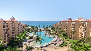 A resort with multiple buildings, a central pool area, and a view of the ocean.