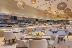 Un restaurante moderno con techos altos, iluminación colgante y una zona de bufé.