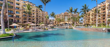 A resort with a large pool, palm trees, and multiple-story buildings.