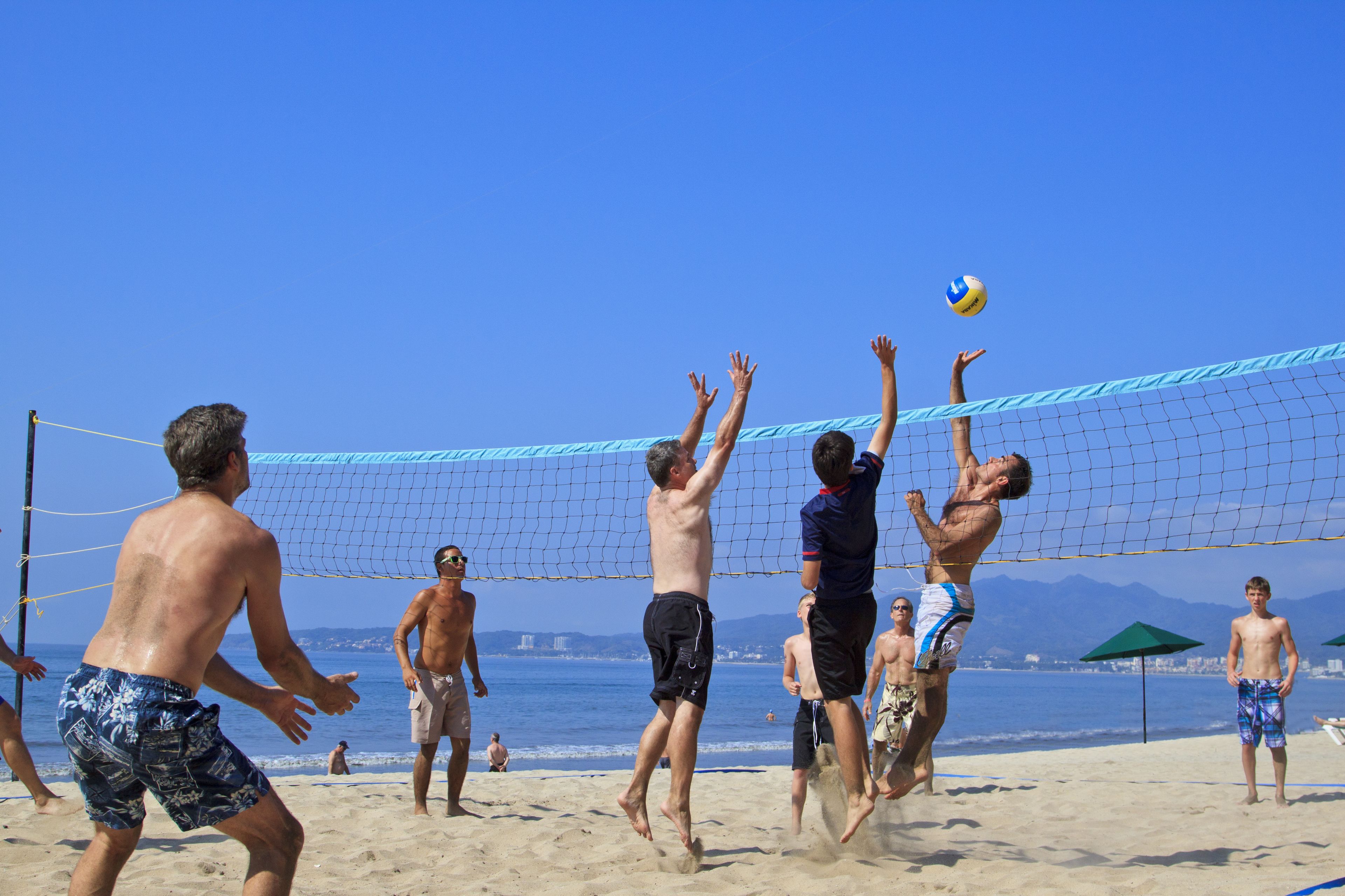 Un partido de voleibol de playa con jugadores saltando para golpear la pelota.