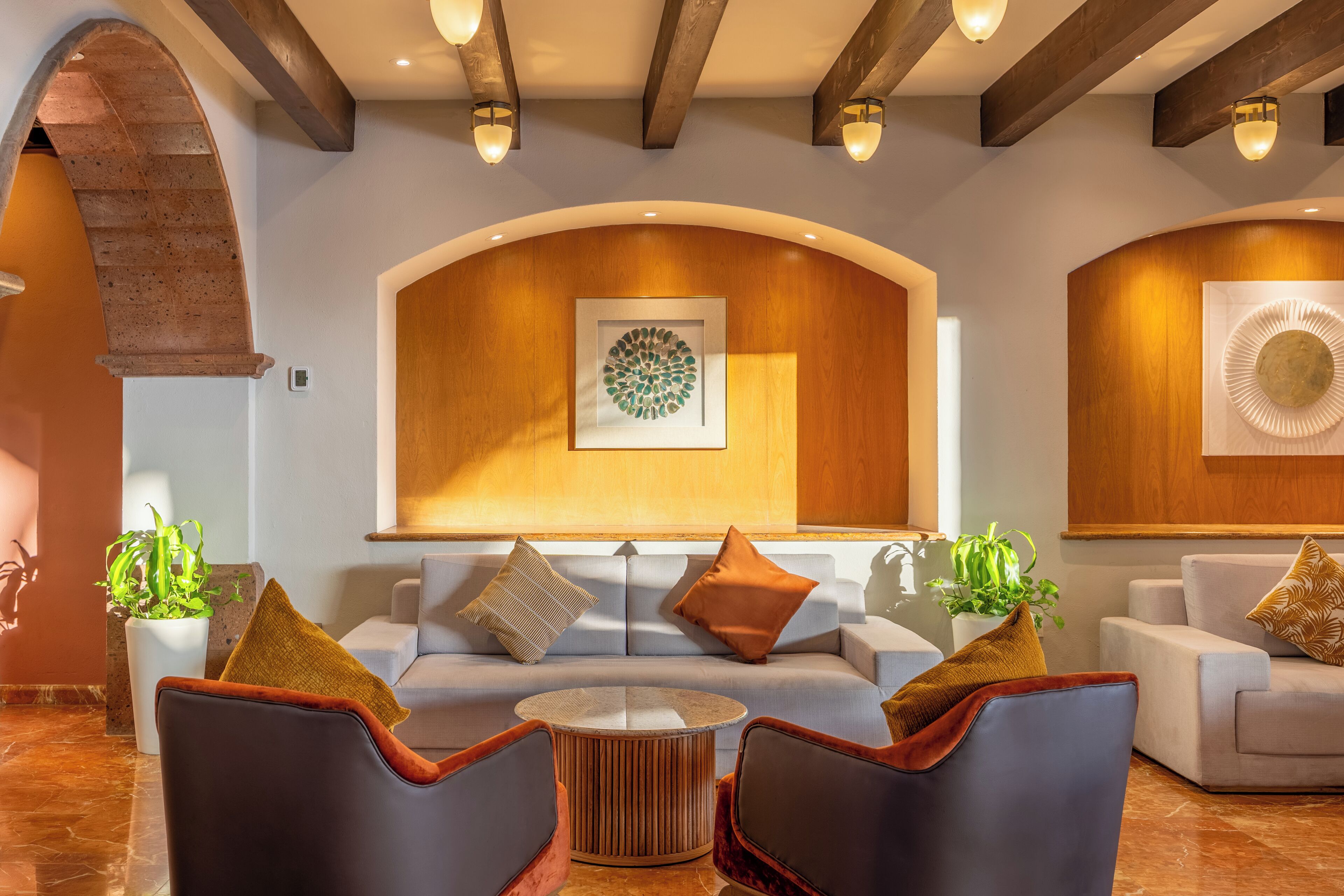 A modern interior with a sofa, chairs, a round table, and decorative wall art.