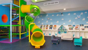 A children's play area with a slide, play structures, and a seating area with toys and books.
