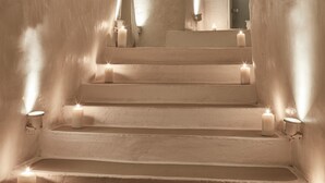 A set of white, arched stairs with candles at each landing, leading to a door at the top. - Notos Therme And Spa by Mr and Mrs White (Santorini)