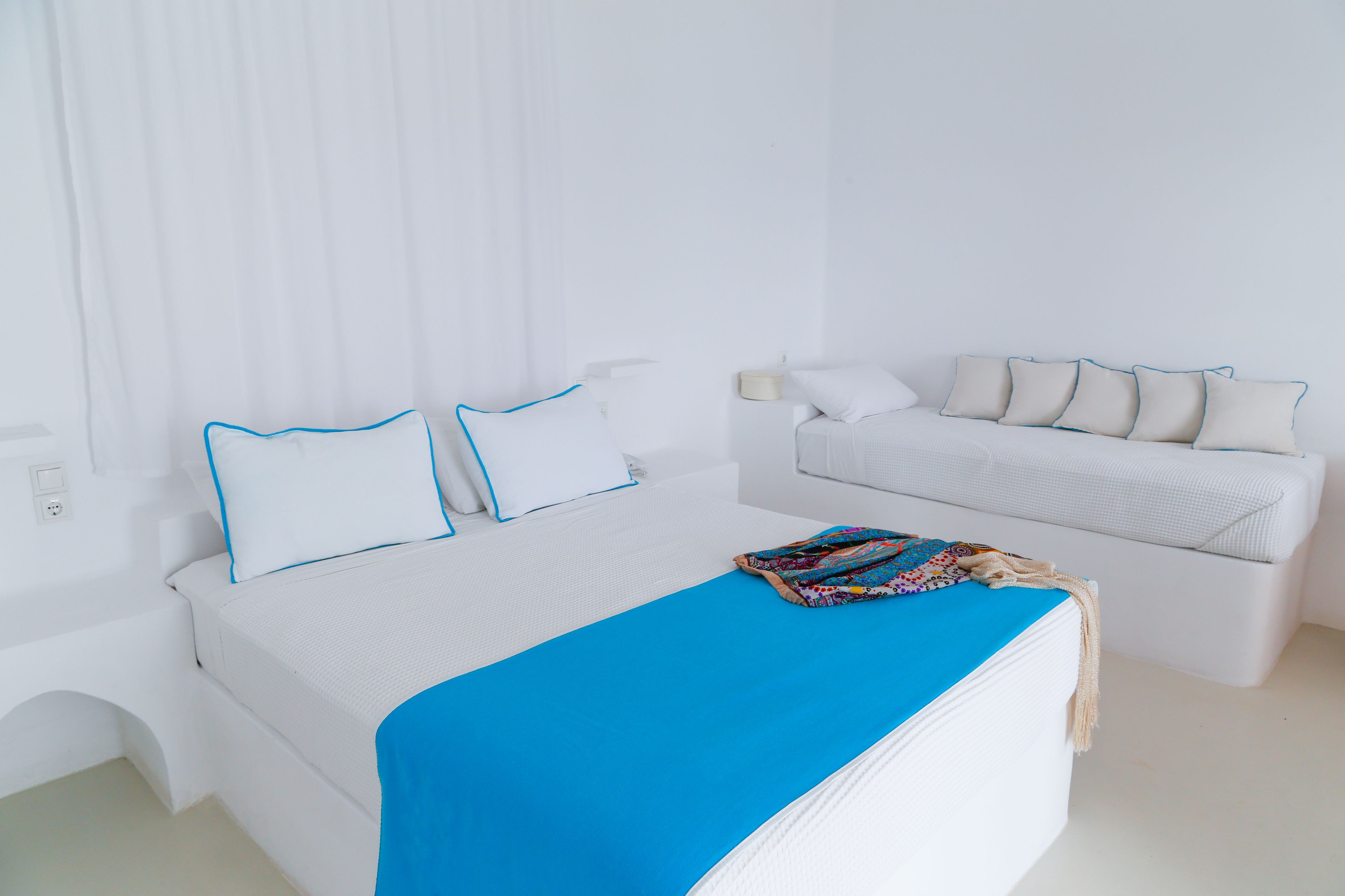 Quarto de hotel com cama, sofá e mesa de cabeceira.