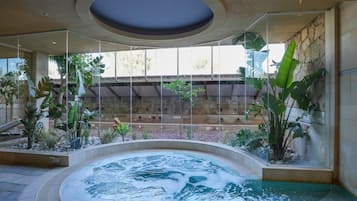 A hot tub area with a stone wall and tropical plants.