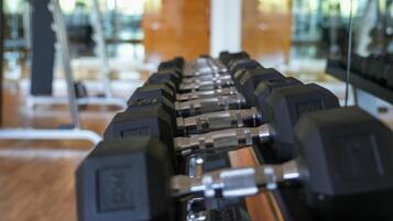 Eine Reihe von Hanteln in einem Fitnessstudio mit Spiegelwänden und Holzboden.