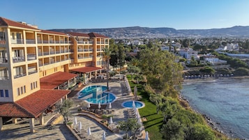 A hotel with multiple balconies, a swimming pool, and a view of the sea.