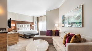 Ein modernes Hotelzimmer mit Bett, Sofa und einem runden Couchtisch.