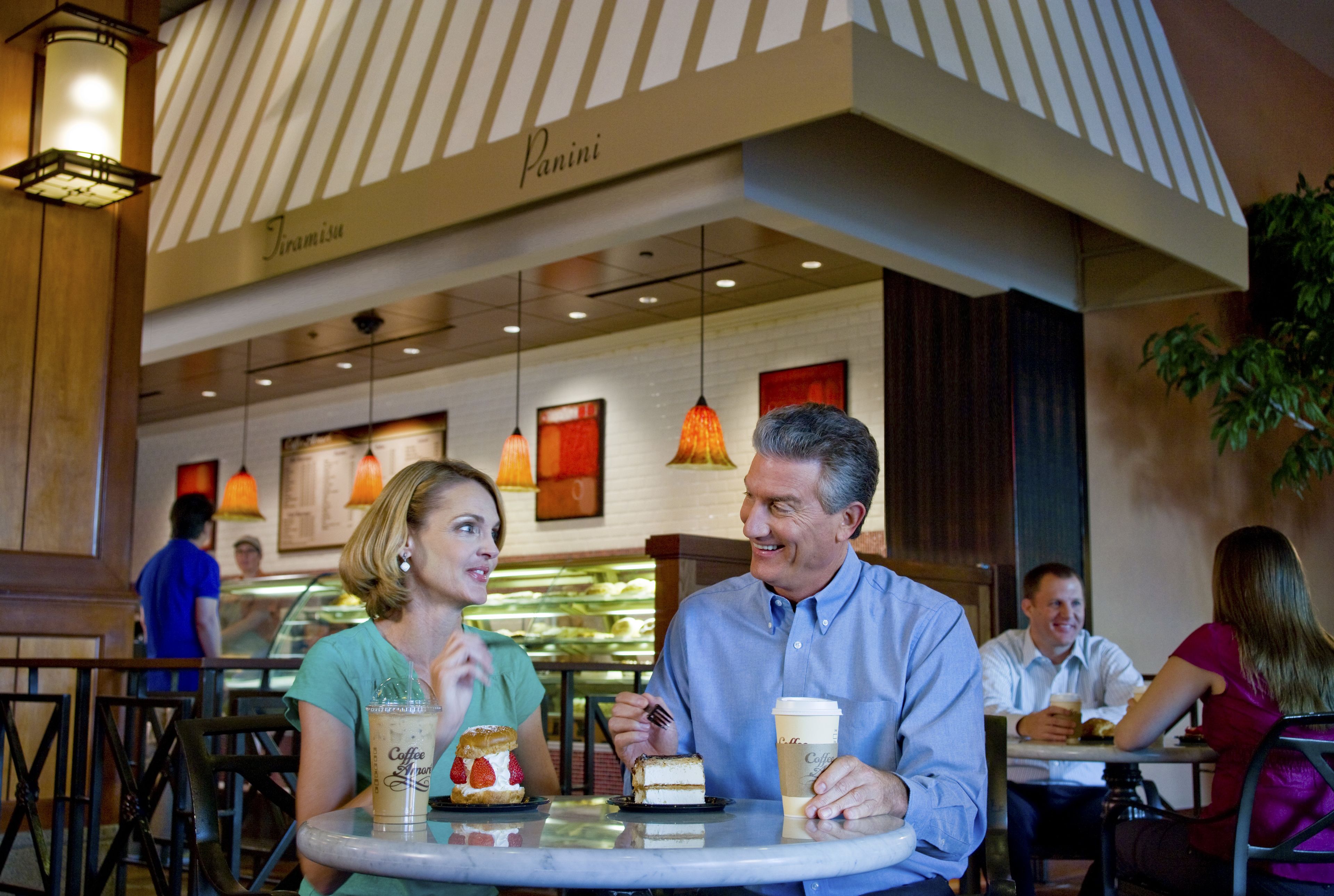 A restaurant with a striped awning and hanging pendant lights.