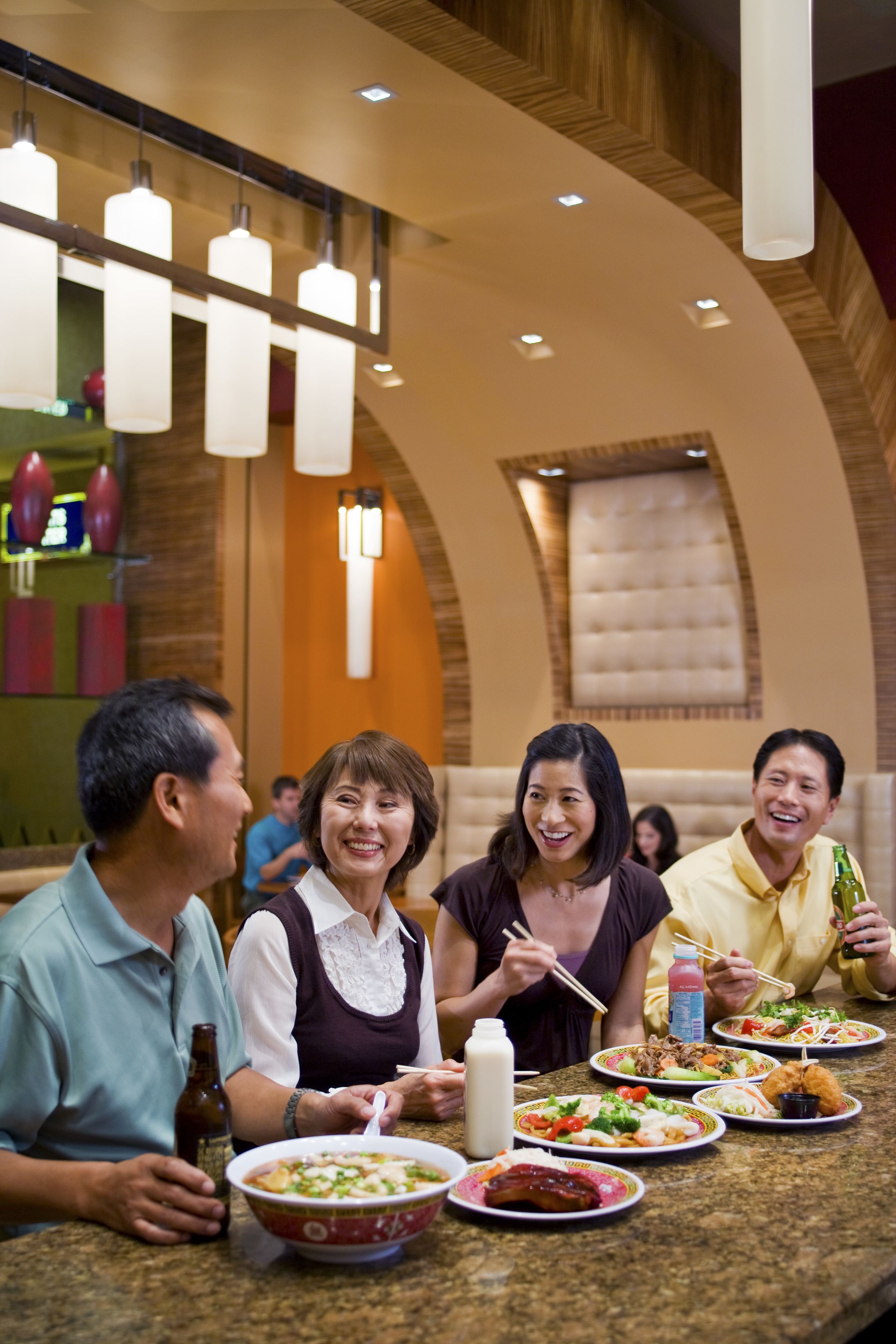 Un grupo de personas cenando en un restaurante con una decoración moderna, que incluye un techo curvo e iluminación colgante.