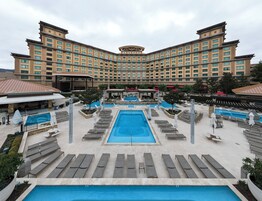 Un hotel con una amplia piscina central, varias zonas de descanso y una arquitectura de edificio distintiva.