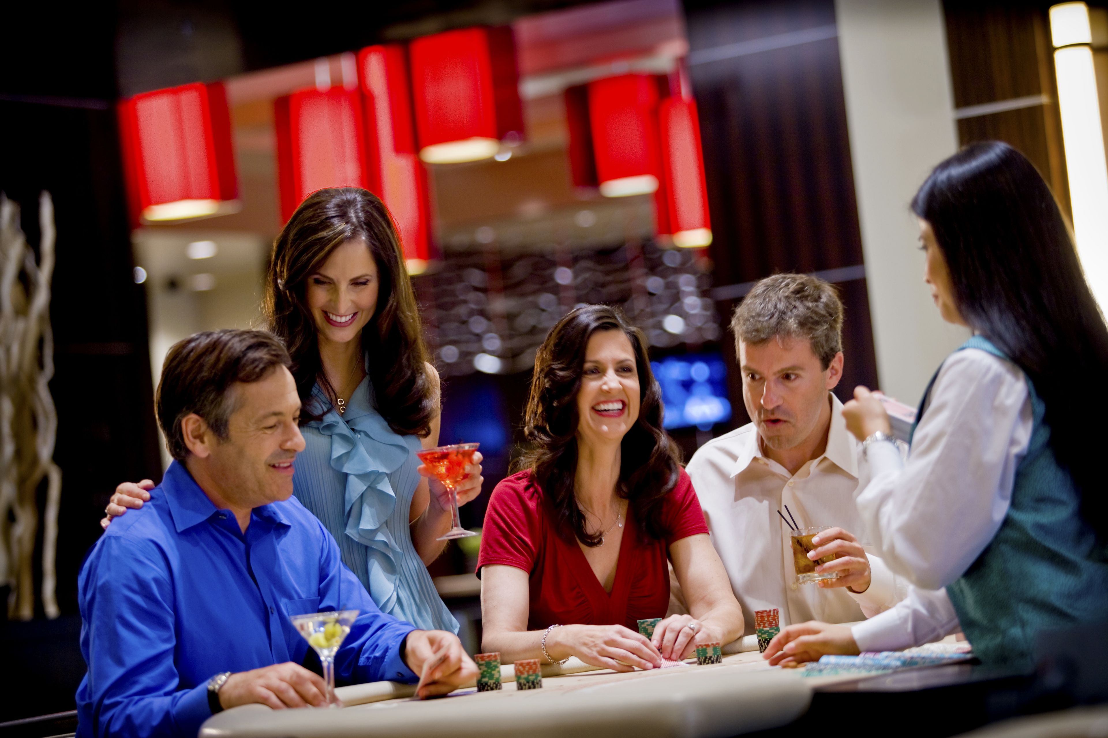Un grupo de personas jugando cartas en una mesa de casino.