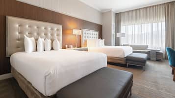 Een hotelkamer met een groot bed, een kleiner bed, een slaapbank, een bureau en een stoel.