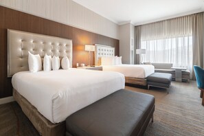 Una habitación de hotel con una cama grande, una cama más pequeña, un sofá, un escritorio y una silla.