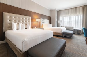 Una habitación de hotel con una cama grande, una cama más pequeña, un sofá, un escritorio y una silla.