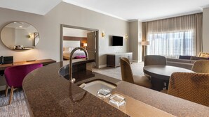 Ein Hotelzimmer mit Küchenzeile, einem Esstisch, einer Couch und einem Fernseher.