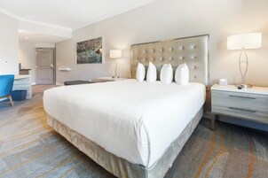 Una habitación de hotel con una cama grande, un escritorio, una silla y un cuadro en la pared.
