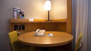 Ein Hotelzimmer mit einem runden Holztisch, einer Schreibtischlampe, einem Telefon und einem Stuhl.