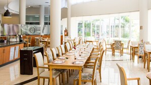 A spacious dining area with long tables and chairs, a kitchen area with a coffee machine, and large windows offering a view of greenery. - Bristol Santo André Hotel (Santo André)