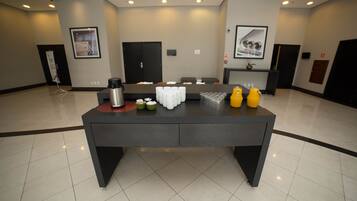 A conference room with a large table, chairs, and a coffee station.
