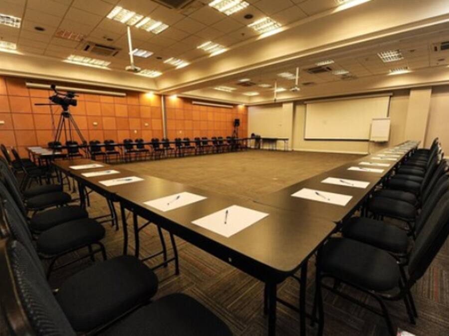 A conference room with a long table, chairs, a projector, and a screen.
