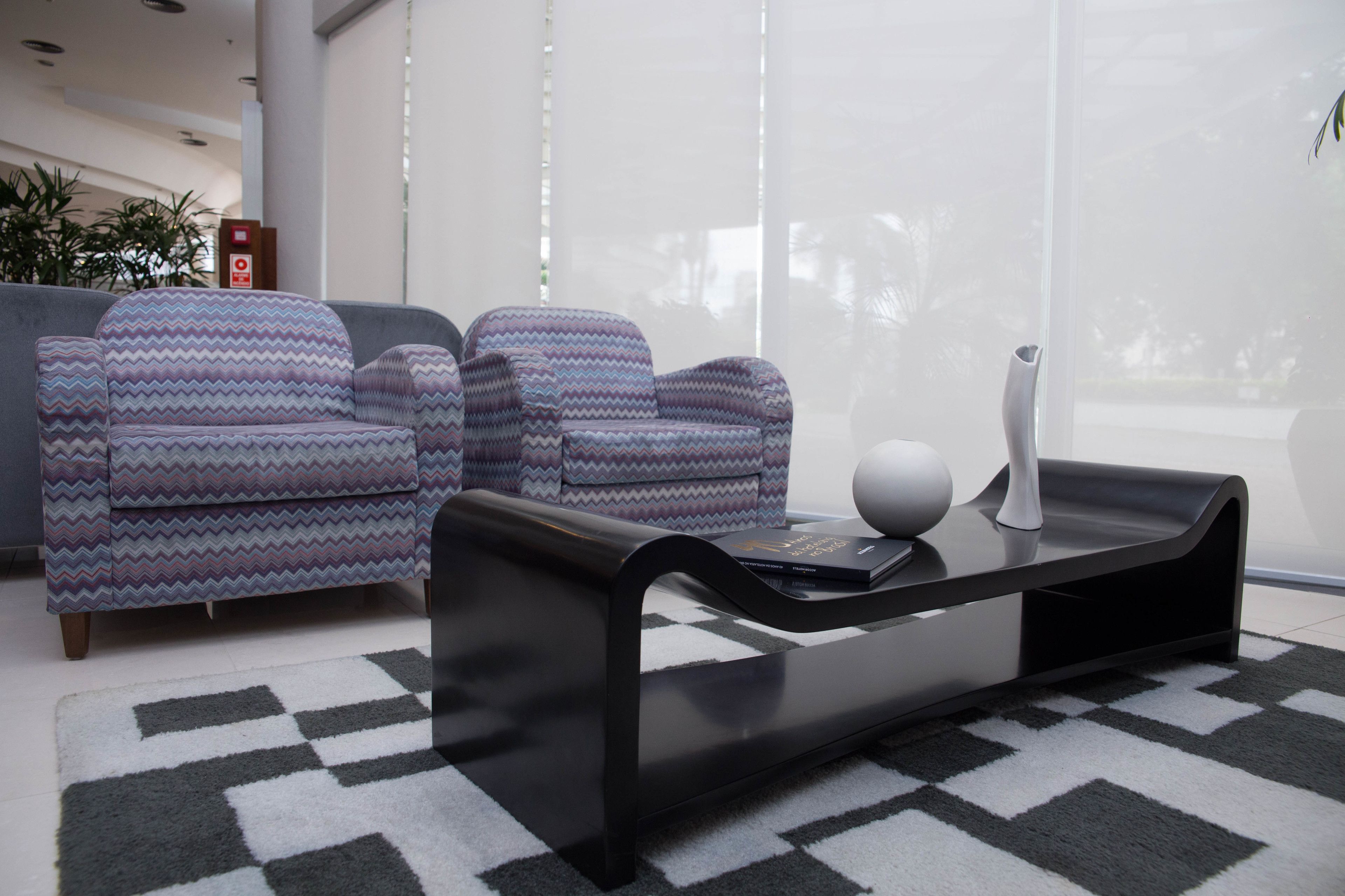 Un espace de vie moderne avec des canapés à motifs, une élégante table basse noire et un tapis à motifs.