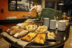 A buffet setup with various breads, pastries, and a decorative orchid centerpiece.