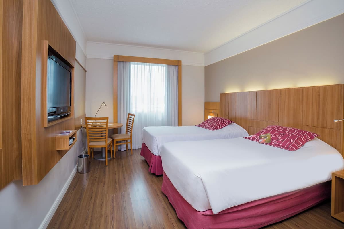 Une chambre d’hôtel avec deux lits, une télévision, un bureau et une chaise.