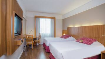 A hotel room with two beds, a TV, a desk, and a chair.