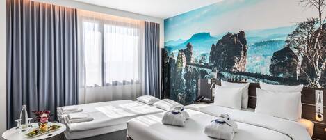 Habitación de hotel con dos camas, una mesita con un jarrón y vasos, y un ventanal con cortinas.