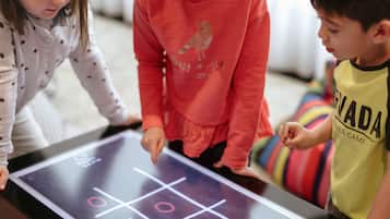 Drei Kinder spielen Tic-Tac-Toe auf einem Tisch.