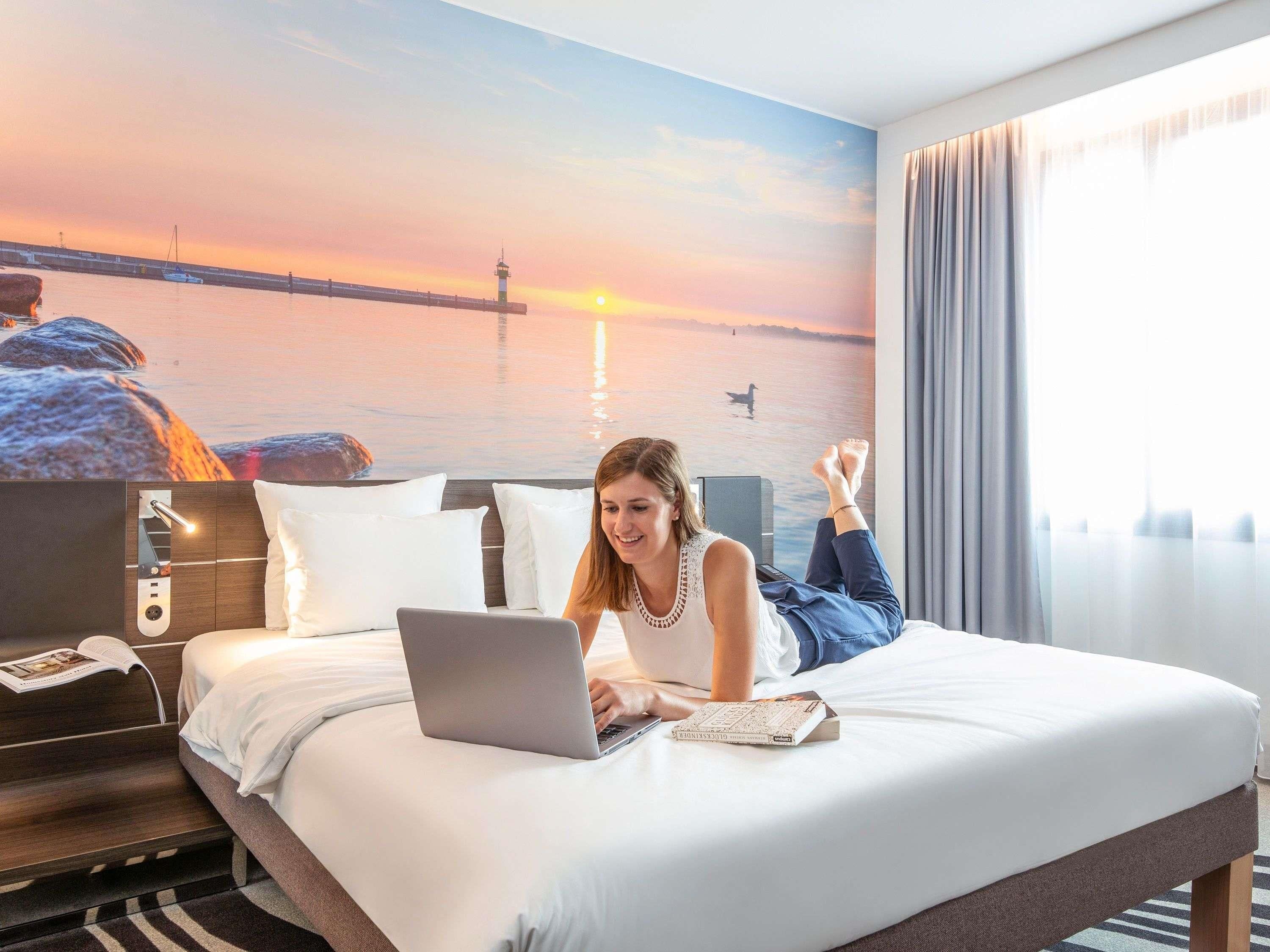 Quarto de hotel com uma cama, um laptop e um livro.