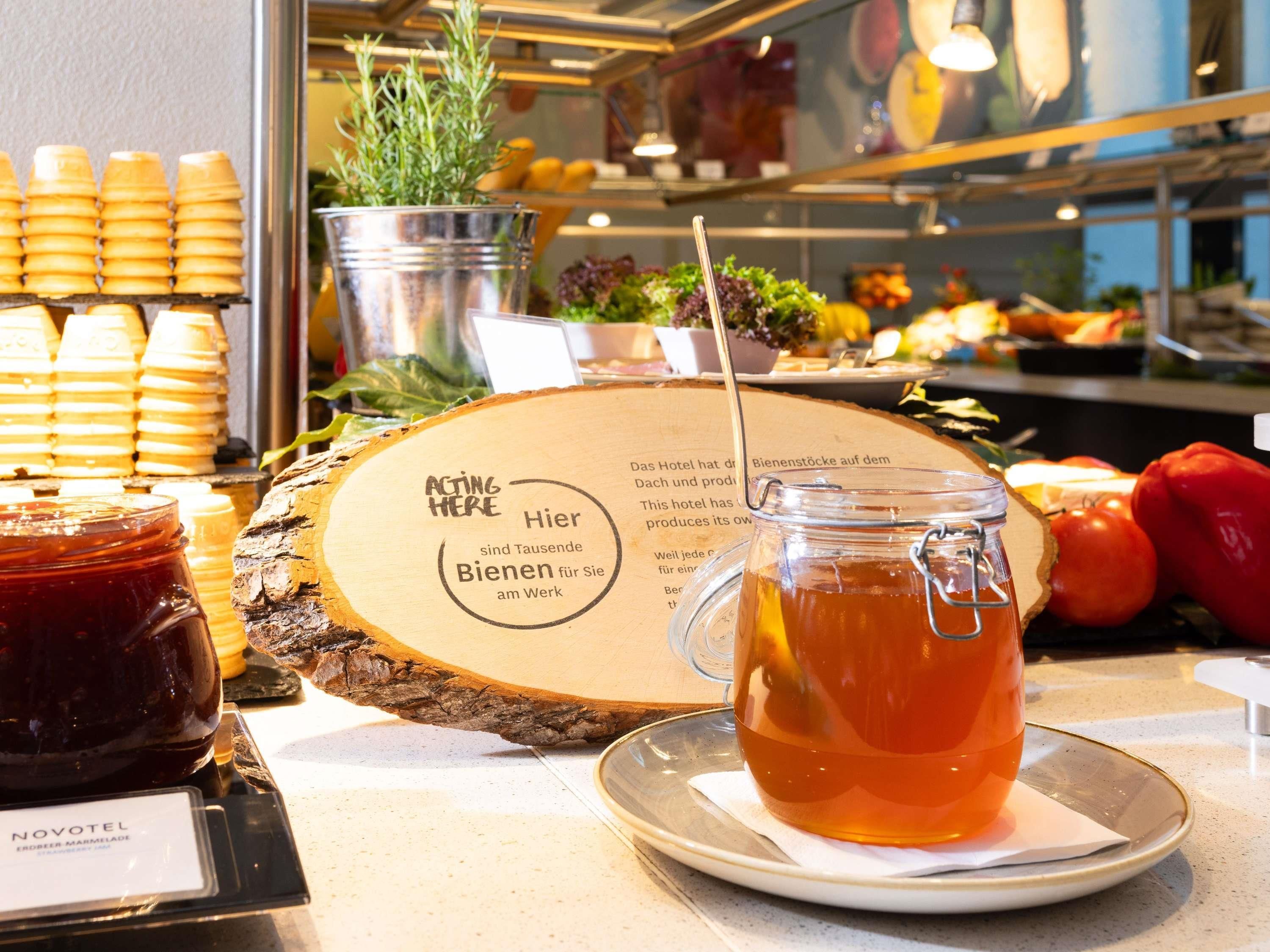 Ein reichhaltiges Buffet mit Bienenwaben, einer Honigdose, einem Teeglas und einem Holzschild mit Schrift.