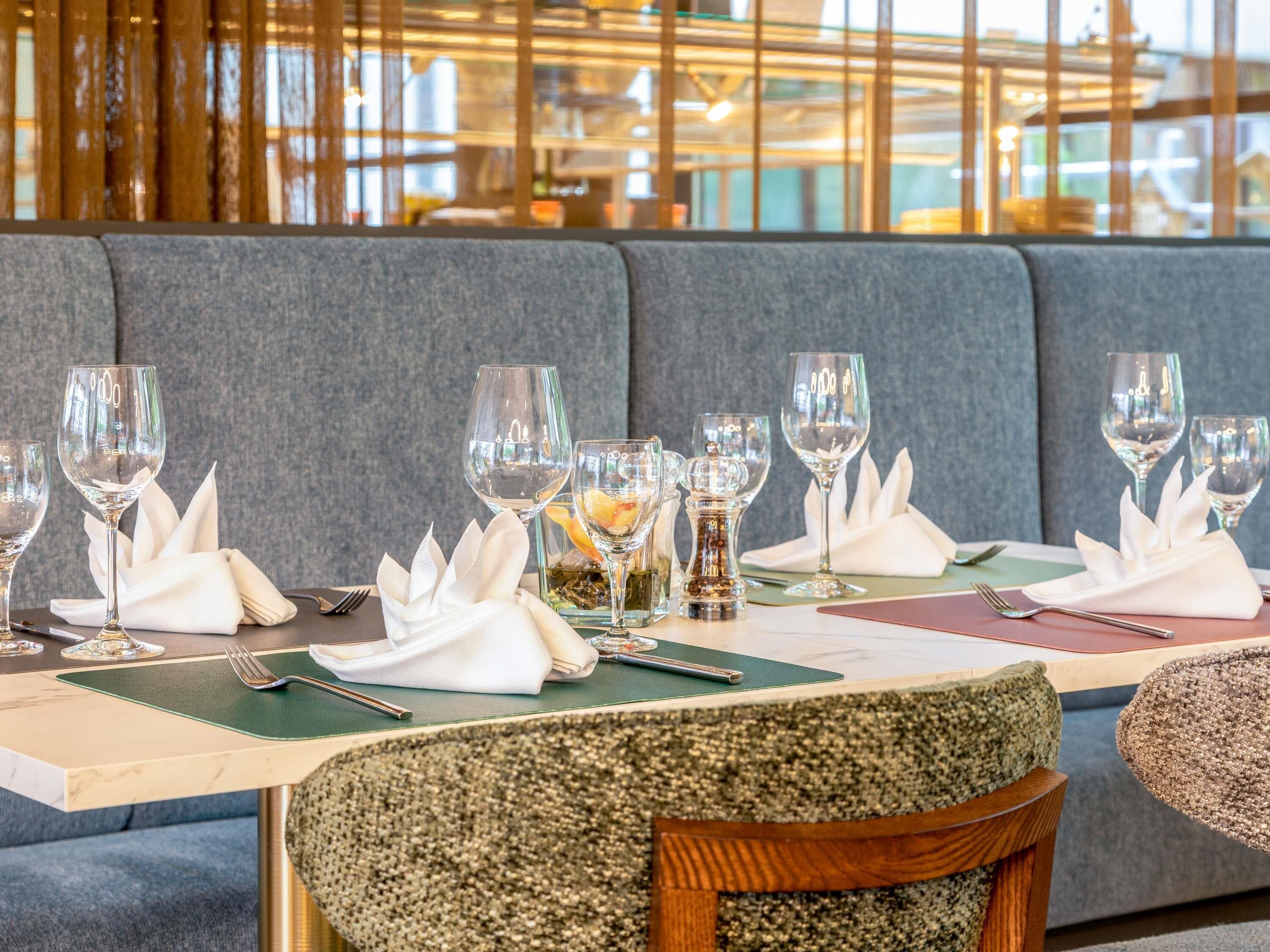 Een restaurantsetting met een gedekte tafel, inclusief wijnglazen, servetten en bestek.