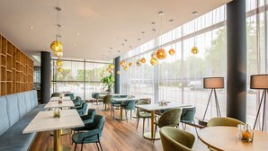Un intérieur de restaurant moderne avec des murs lambrissés en bois, de grandes fenêtres et différents types de sièges, notamment des tables et des banquettes.