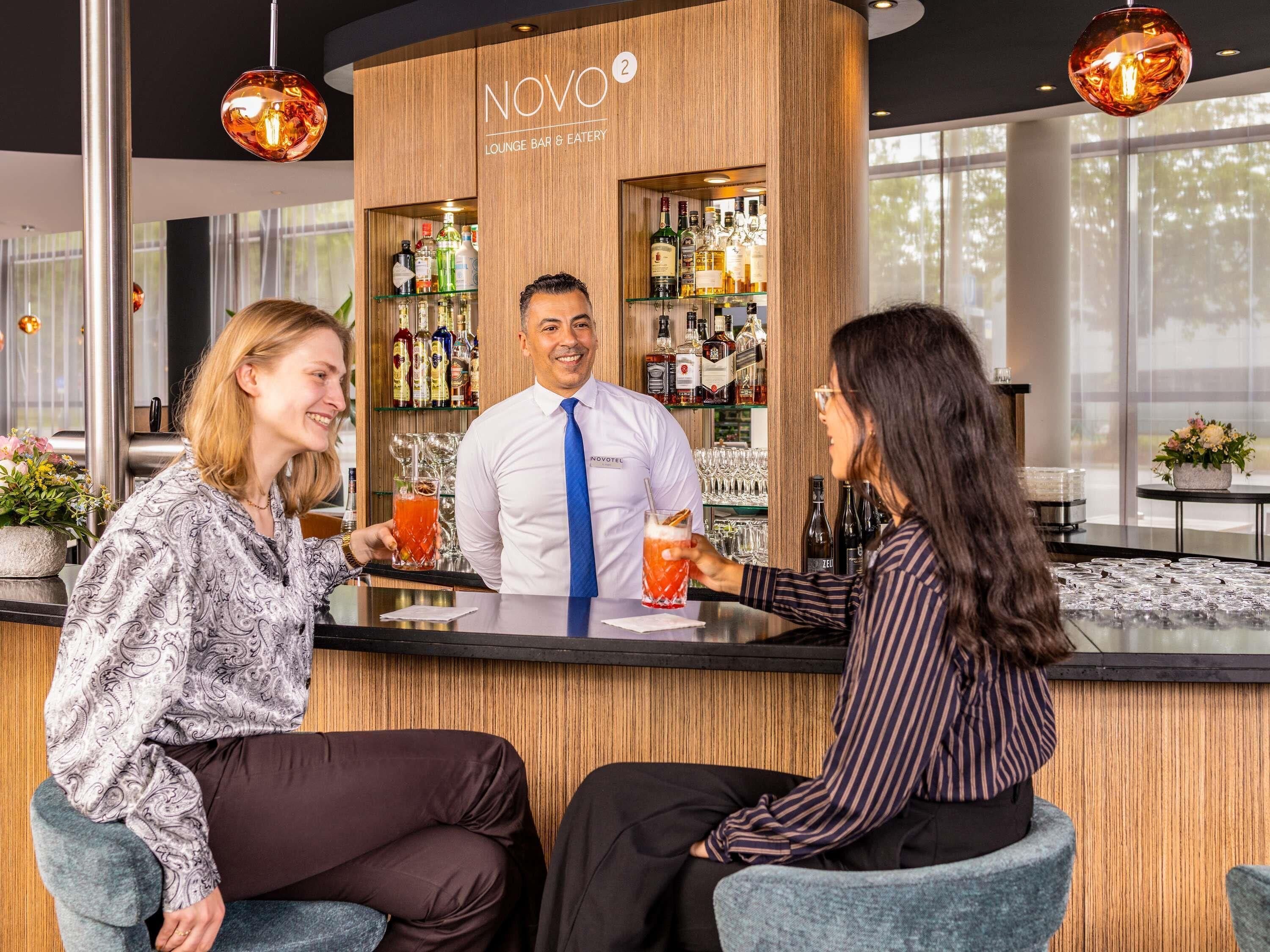 Un espace bar avec un comptoir en bois, des tabourets de bar et un barman.