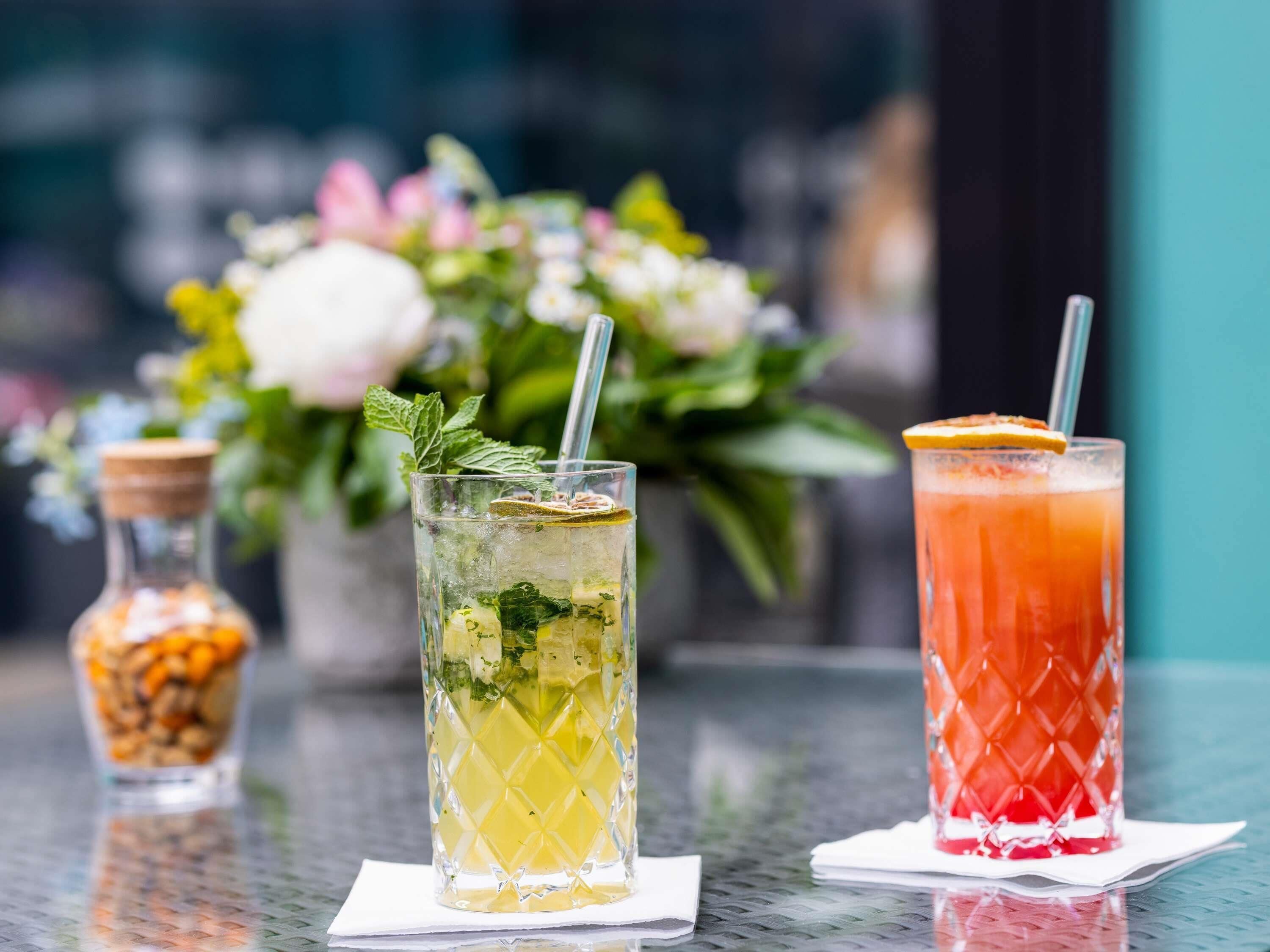 Drie glazen drank op een tafel, met een vage achtergrond van bloemen.