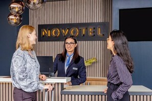 Un mostrador de recepción con un cartel que dice 'NOVOTEL' y un diseño interior moderno.