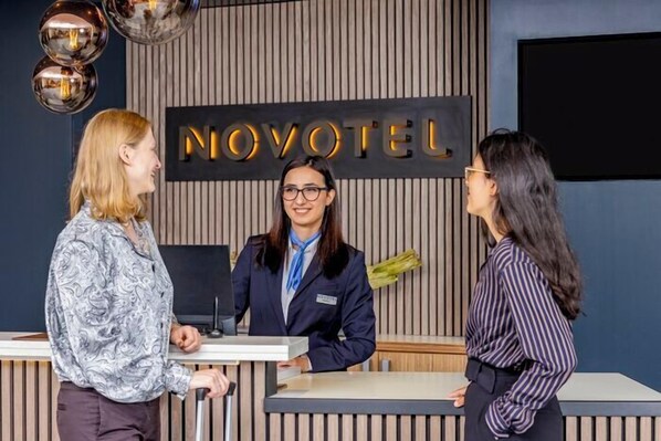 A reception desk with a sign reading 'NOVOTEL' and a modern interior design. - Novotel Hamburg City Alster (Hamburg)