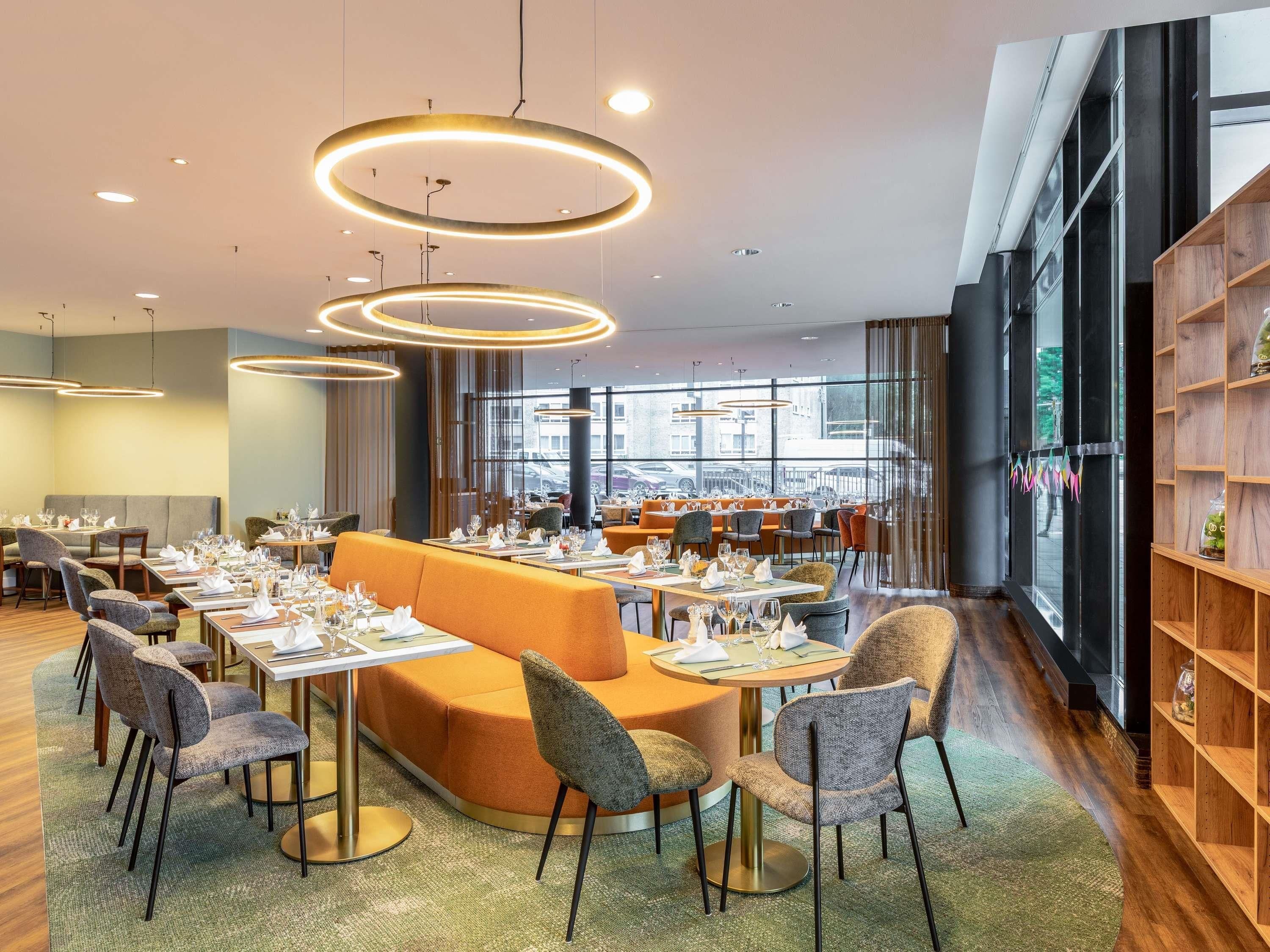 A modern dining area with round tables, cushioned seating, and pendant lighting.