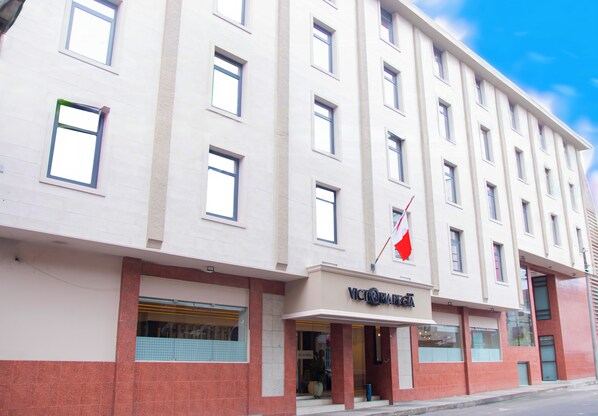 A multi-story hotel with a flat facade, large windows, and a flag on the corner. - Victoria Regia Hotel (Iquitos)