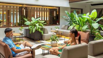 A spacious indoor area with a high ceiling, large windows, and multiple seating arrangements.