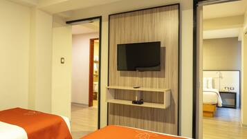Ein Hotelzimmer mit einem Bett, einem an einer Holzplatte montierten Fernseher und einem Nachttisch mit Telefon und Lampe.
