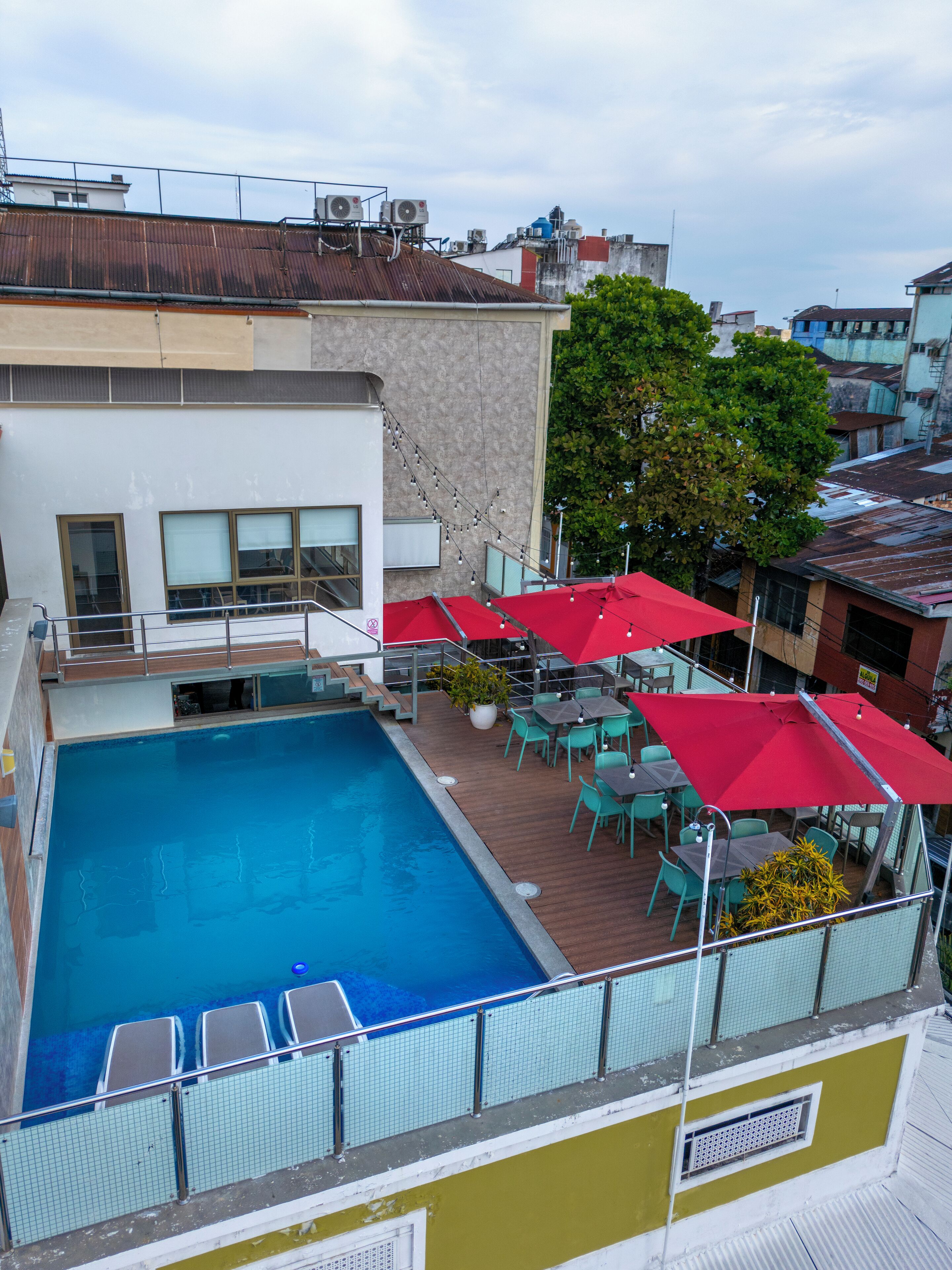 A rooftop pool area with a swimming pool, outdoor seating, and umbrellas.