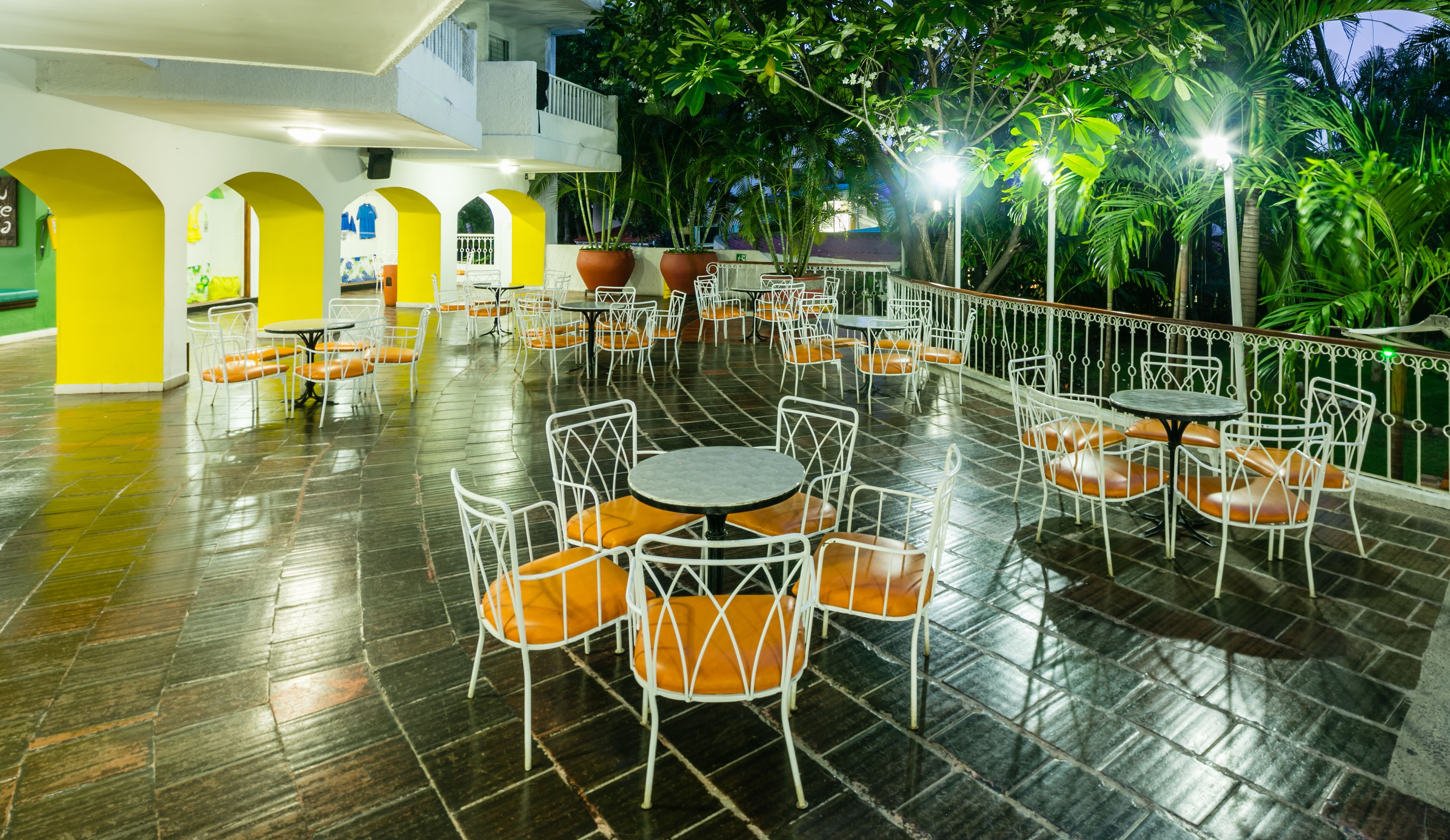 Een terras met meerdere tafels en stoelen, omringd door een balustrade en potplanten.