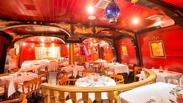 A restaurant with wooden interiors, round tables, and chairs.