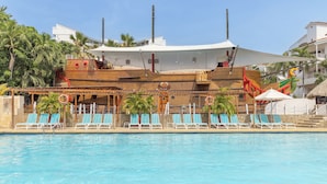 A swimming pool with lounge chairs and a tiki bar structure.