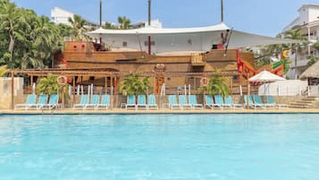 Relax by the pool surrounded by palm trees and a unique ship-themed structure.