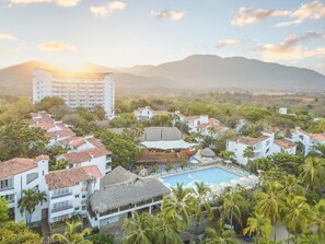 A resort with a swimming pool, multiple buildings, and palm trees.