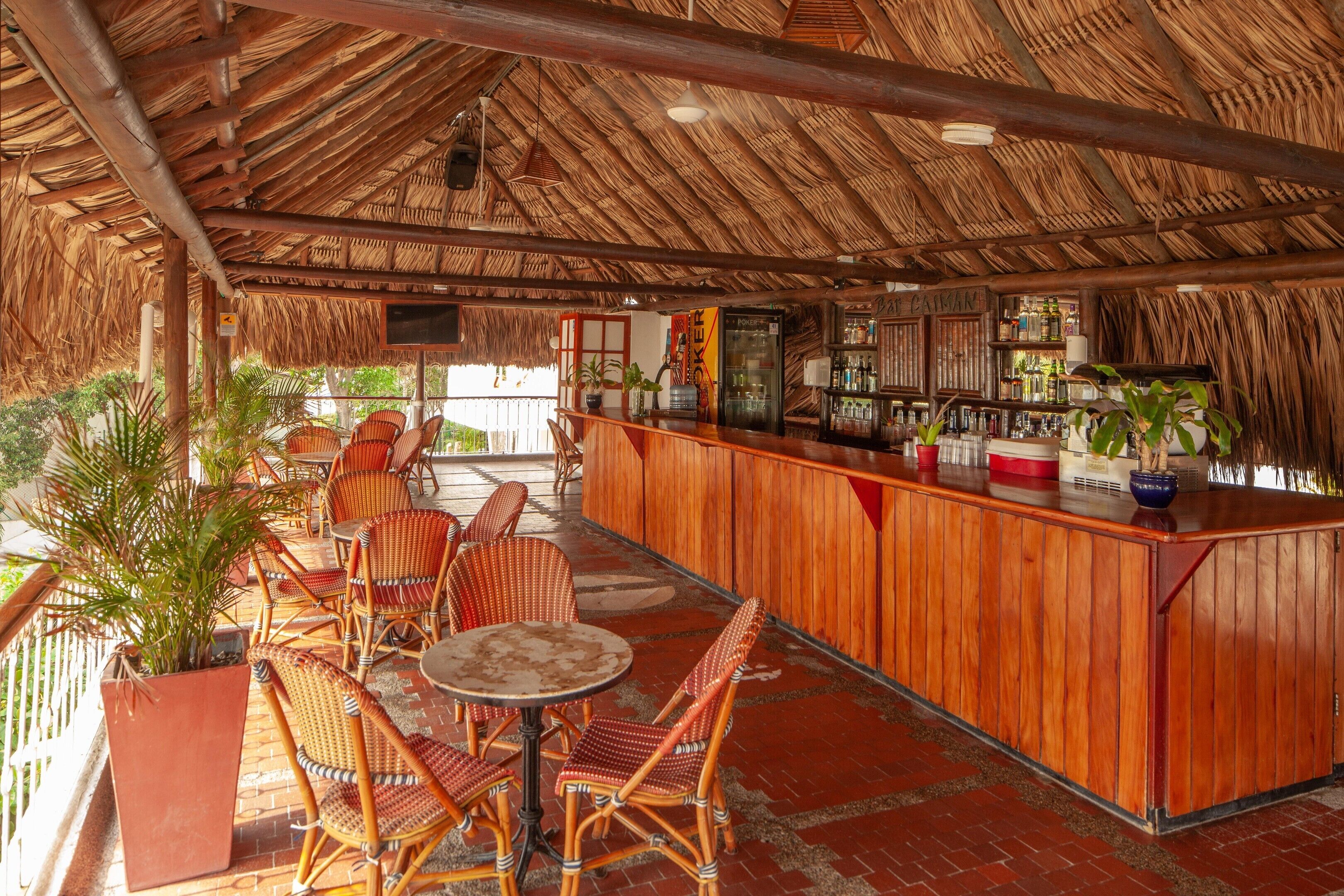 A bar area with wicker furniture and a thatched roof.